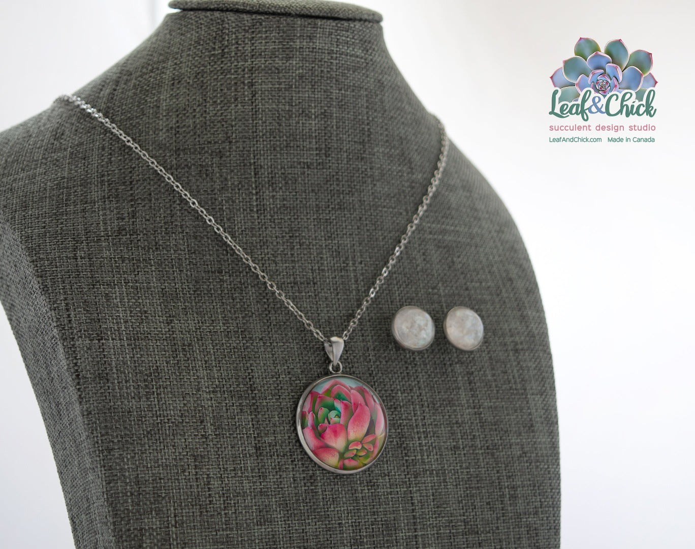 Pink succulent art necklace displayed on a grey form with small round shimmery studs