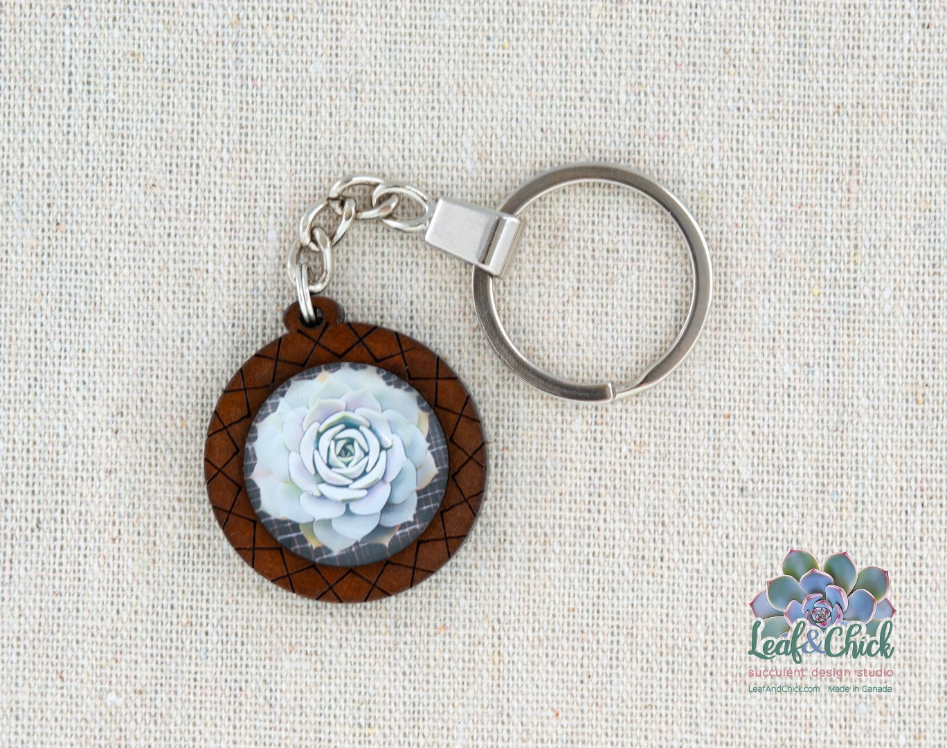 close up of hashed wood keychain with white echeveria art