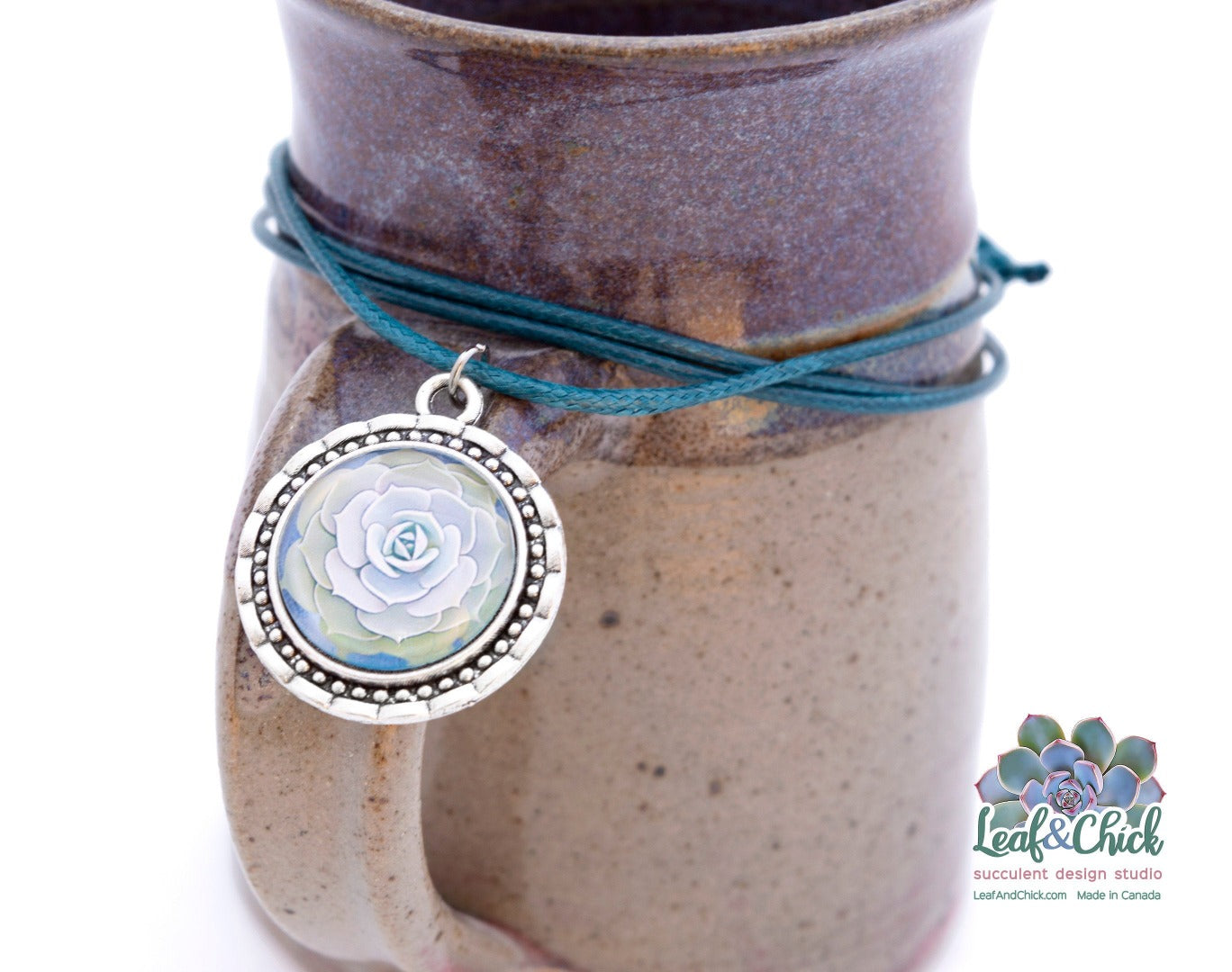 close up of antique silver pendant with light green succulent art and blue cord